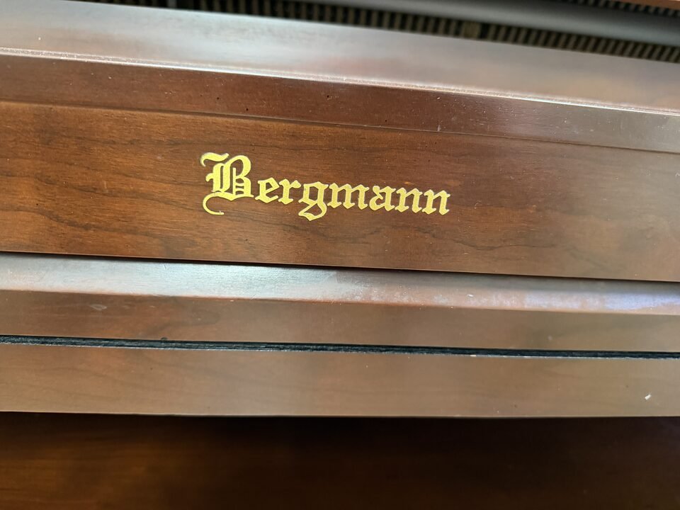 Bergmann brand name in gold lettering on a walnut upright piano